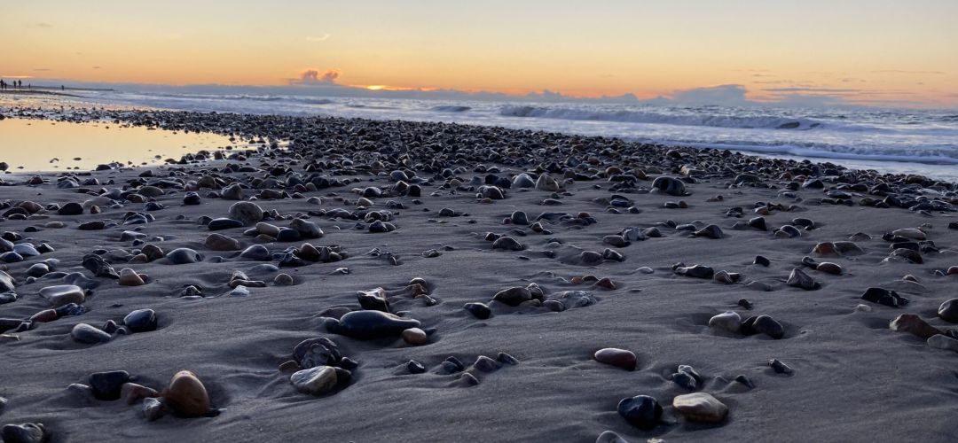 Solnedgang den 26. januar 2021 ved Tornby Strand. Smukke sten med bølger i baggrunden.