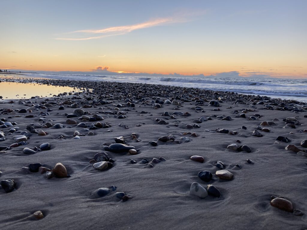 Solnedgang den 26. januar 2021 ved Tornby Strand. Smukke sten med bølger i baggrunden.