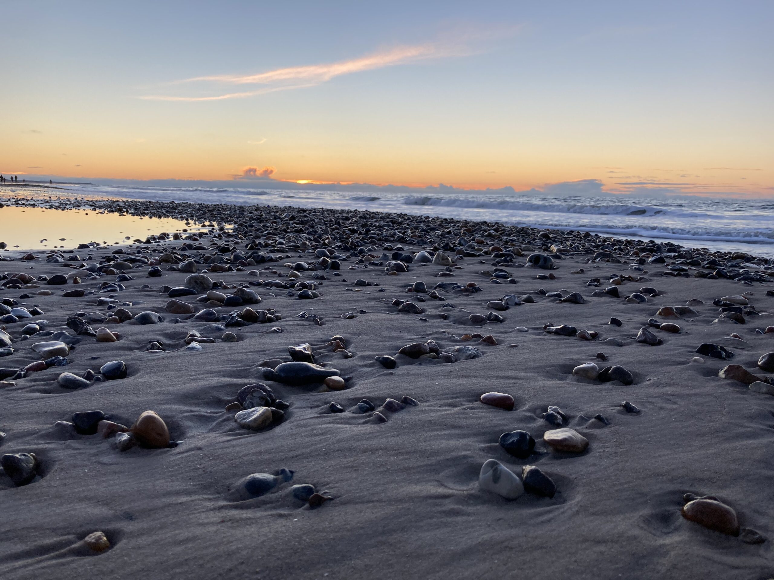 Solnedgang den 26. januar 2021 ved Tornby Strand. Smukke sten med bølger i baggrunden.